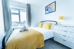 Un dormitorio con una cama con almohadas amarillas y una ventana. en Stunning 4-Bed Beachfront Home Sea Views in Dymchurch, en Dymchurch