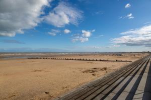 Un muelle en la playa con un cielo azul y nubes. en Stunning 4-Bed Beachfront Home Sea Views in Dymchurch, en Dymchurch