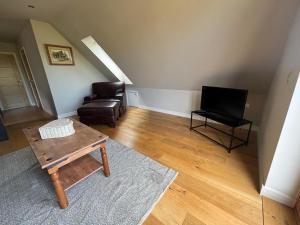 Una sala de estar con una silla y un televisor. en Tranquil Pond View Loft Retreat in Sudbury, en Bulmer