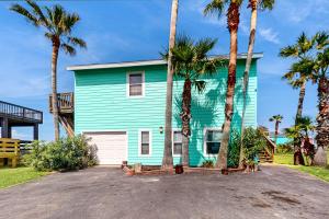 a blue house with palm trees in front of it at Lost Colony Lost Sea Turtle in Port Aransas