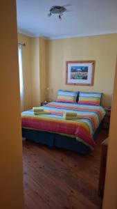a bedroom with a large bed with colorful sheets and pillows at The Cottage, Heide Avenue in Somerset West