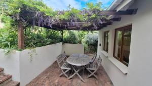 a patio with a table and chairs on the side of a house at The Cottage, Heide Avenue in Somerset West +2 photos