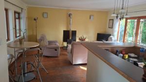 a kitchen and living room with a couch and a table at The Cottage, Heide Avenue in Somerset West