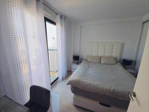 a white bedroom with a bed and a window at Cozy, modern, two-level apartment in Orihuela Costa