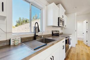 a kitchen with white cabinets and a sink and a window at Trails & Tranquility in Pagosa Springs