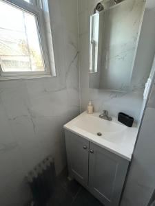 Un baño blanco con lavabo y espejo. en Cozy modern Bellerose, en Bellerose