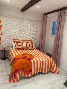 a bedroom with a bed with an orange and white striped comforter at Le pop Daudet in Fontvieille