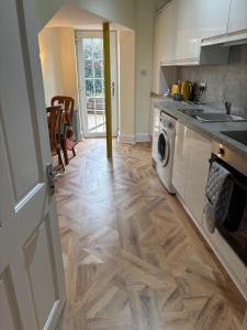 a kitchen with a washing machine and a wooden floor at Crescent Corner 44 Seamore Str Ground Floor Right in Largs +23 photos