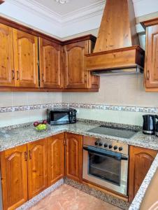 a kitchen with wooden cabinets and a stove top oven at CHC - Apartamento Los Silos Tulipanes 1 in Los Silos