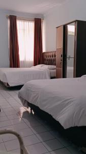 a bedroom with two beds and a couch in it at Hotel Inayah Syariah in Kumprung