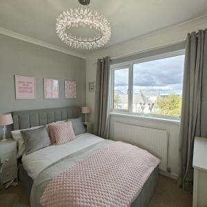 a bedroom with a bed with a chandelier and a window at 3 Bed in Pentlepoir oc-a33527 in Kilgetty