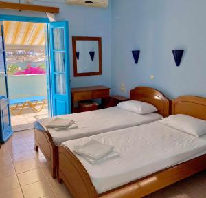 ein Schlafzimmer mit zwei Betten und einer Tür zum Balkon in der Unterkunft Sevasti Studios in Panormos Kalymnos