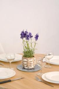 a table with plates and glasses and a vase with purple flowers at Le Bourgneuf in Chartres