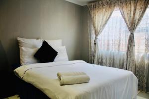 a bedroom with a white bed with a window at Newlands Comfortable Abode in Johannesburg