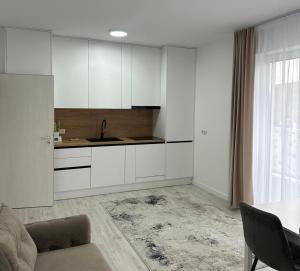 a kitchen with white cabinets and a table and a couch at Apartament panoramic in Bistriţa