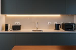 a kitchen counter with a sink and a microwave at Vintage 2-Bed Apt with Music Room in Fundão