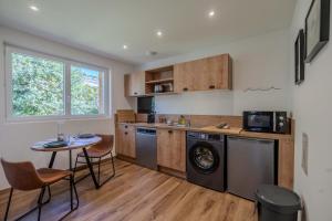 a kitchen with a washing machine and a table at L'Ostalet suite luxe Jacuzzi in Ax-les-Thermes