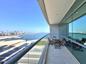 einen Balkon mit Tischen und Stühlen und Blick auf das Wasser in der Unterkunft Modern comfort in a compact spacious studio one or two bedroom retreats in Manama