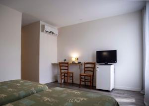 a room with a bed and a tv and a table at Les Ambassadeurs Logis Hotels et Restaurant in Souillac