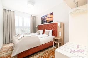 a bedroom with a large bed with a wooden headboard at Your Holidays Komfortowy Apartament Bel Mare 213 F, Parking Gratis in Międzyzdroje
