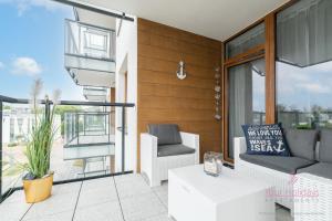 a patio with a couch and a chair on a balcony at Your Holidays Komfortowy Apartament Bel Mare 213 F, Parking Gratis in Międzyzdroje