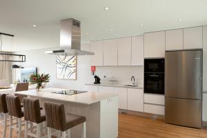 a kitchen with white cabinets and a kitchen island with chairs at Villa Joy, moderna e sofisticada in Funchal