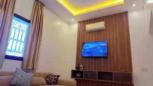 a living room with a couch and a tv on a wall at Appartement Aéroport Sunset Marrakech in Marrakesh