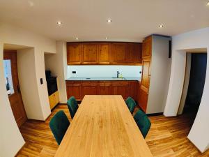 a kitchen with a long wooden table and green chairs at Chasa Salnuun Ferienwohnungen in Samnaun