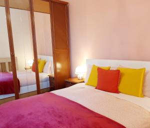 a bedroom with a bed with colorful pillows and a mirror at Fiori e Frutti Sunshine Home in Almese