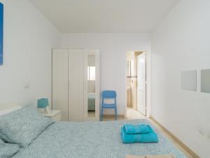 ein Schlafzimmer mit einem blauen Bett und einem blauen Stuhl in der Unterkunft Pura Vida - 10 min de Maspalomas y Aeropuerto in Vecindario