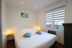 1 dormitorio con 1 cama blanca y 2 almohadas azules en Le CapriBeach by Tranquil at Home, en Pornichet 14 fotos más