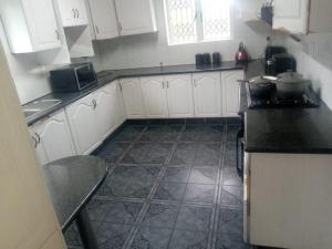 a kitchen with white cabinets and a tile floor at B and B Sunblue in Durban