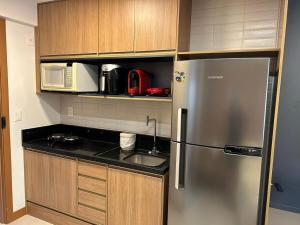 Una cocina con refrigerador de acero inoxidable y microondas. en Studio Barra Salvador -, en Salvador