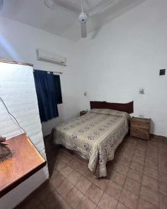 Un dormitorio con una cama en una habitación blanca. en Complejo Villa del sol, en Mina Clavero