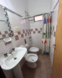 Un baño con lavabo, inodoro y cortina de ducha. en Complejo Villa del sol, en Mina Clavero