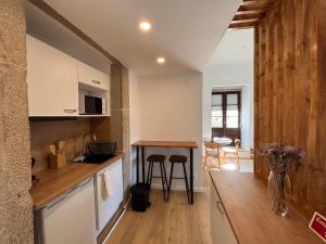 a kitchen with white cabinets and a wooden floor at Villa Matriz Suite Apartment in Caminha