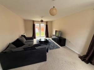 ein Wohnzimmer mit einer schwarzen Couch und einem Fernseher in der Unterkunft Charming Aylesbury Retreat with 4 Bedrooms in Weedon