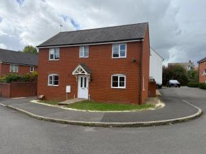 ein rotes Backsteinhaus mit einer weißen Tür an einer Straße in der Unterkunft Charming Aylesbury Retreat with 4 Bedrooms in Weedon