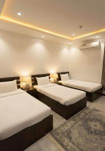 une chambre avec deux lits et un tapis dans l'établissement شقق نرمادا المفروشة 303, à Médine 3 autres photos