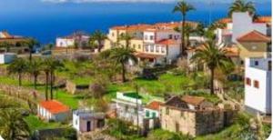 a group of houses with palm trees and the ocean at La Maestra Apartment in Alajeró