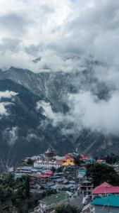 a group of buildings in a city with a mountain at Derainkalpa in Chini