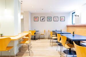 a dining room with blue tables and yellow chairs at Garner Hotel Cologne East by IHG in Cologne