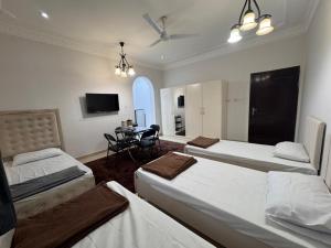 a bedroom with three beds and a table and a tv at Muscat Guesthouse 3 All Private Ensuite Rooms in Muscat