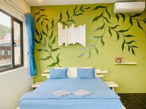 a bedroom with a blue bed with leaves painted on the wall at The Little Leaf Hostel - Restaurant & Rooptop Bar in Cat Ba