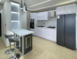 a kitchen with white cabinets and a counter and a refrigerator at Hospedaje Talisman in Pichilemu
