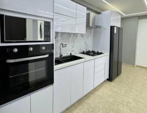a kitchen with white cabinets and a microwave and a sink at Hospedaje Talisman in Pichilemu