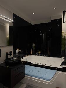 a bathroom with a large tub with black walls at LTS RENT Luxury&Comfortable PREMIUM Letnica Villa in Gdańsk