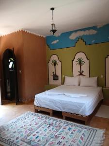 a bedroom with a bed with palm trees painted on the wall at AUBERGE DES ANGES in Zrigat