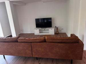 a brown couch in a living room with a tv at Luxury Apartment nähe Düsseldorf in Wuppertal