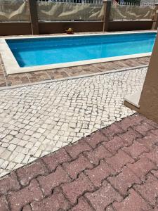 a swimming pool next to a house with a tile floor at Holiday Villa with Private Pool - Villa Farol in Nazaré